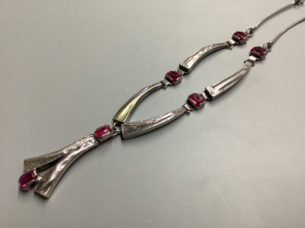A modern stylish white metal and synthetic ruby set drop pendant necklace, 55 cm.